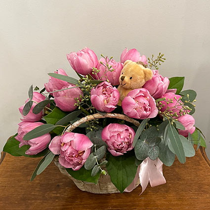 Small basket of pink flowers and teddy bear